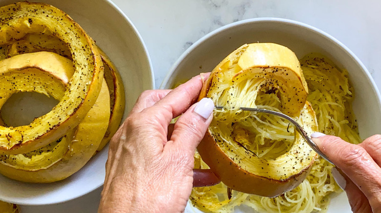 hands shredding cooked spaghetti squash