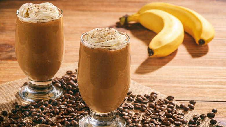 Two glasses of banana coffee next to fresh bananas 