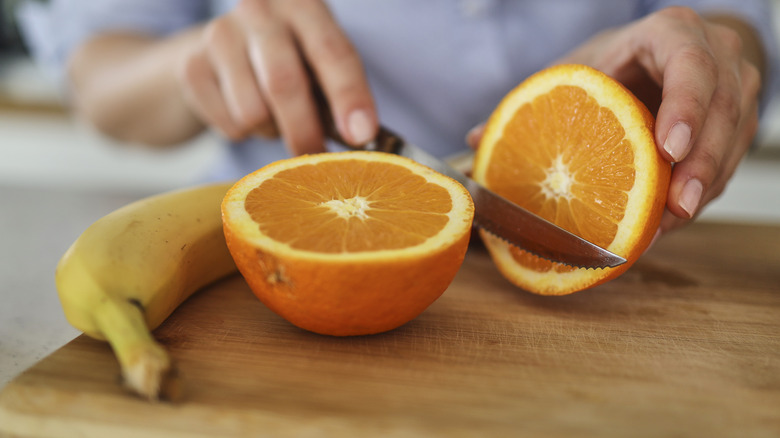 hand chopping orange and banana