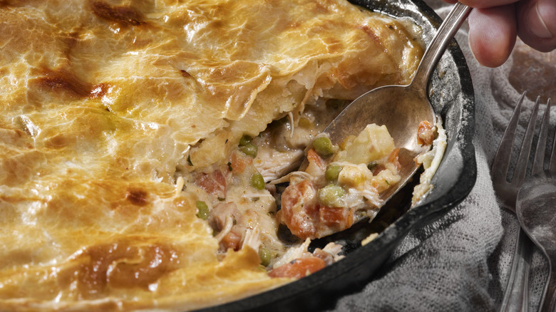 A chicken pot pie being eaten with a spoon.