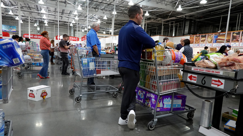 Costco customers in lines waiting to check out with carts full of large purchases