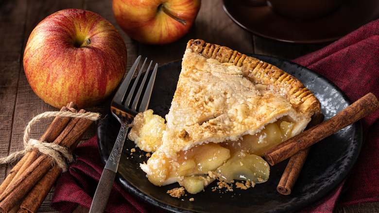 Slice of apple pie with cinnamon sticks