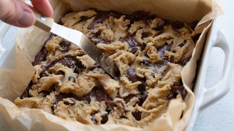 Spatula swirling cookie dough into brownie batter