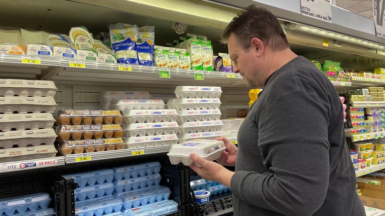 Man checking egg prices in a grocery store