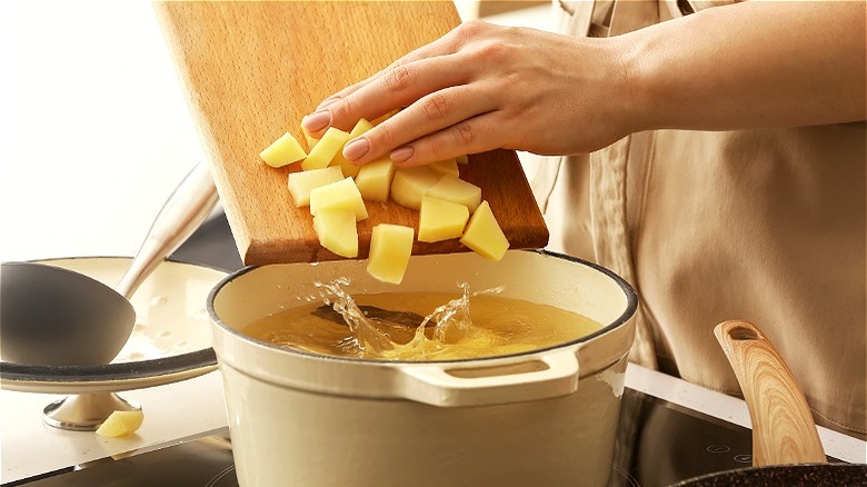 Hand putting potatoes in pot