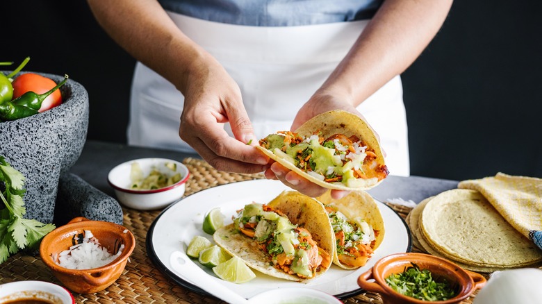 A person making al pastor tacos 