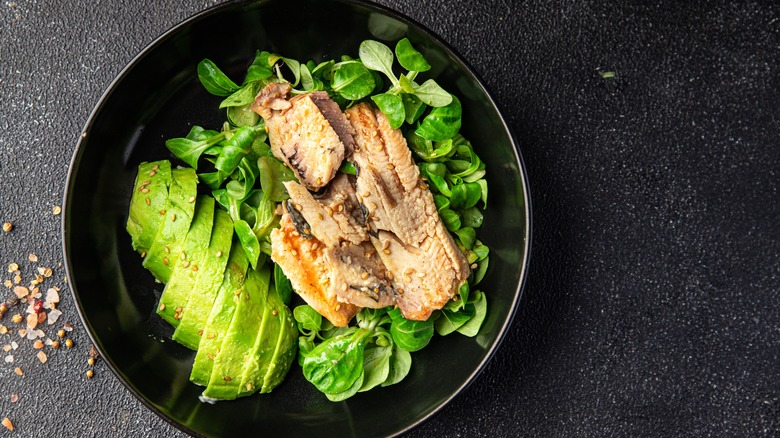 A sardine salad with greens and avocado
