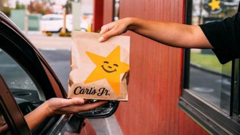 Carl's Jr drive thru employee handing bag