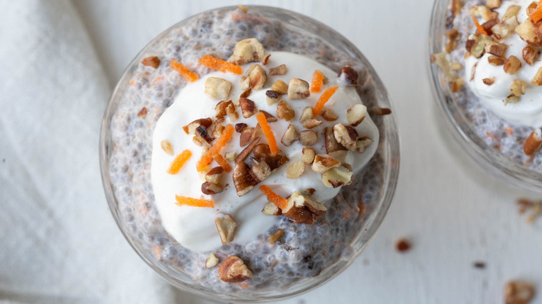 Carrot cake chia pudding in cup with yogurt, chopped nuts, and carrot toppings