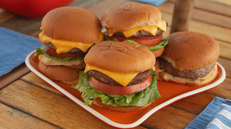 Four hamburgers on plate with various toppings