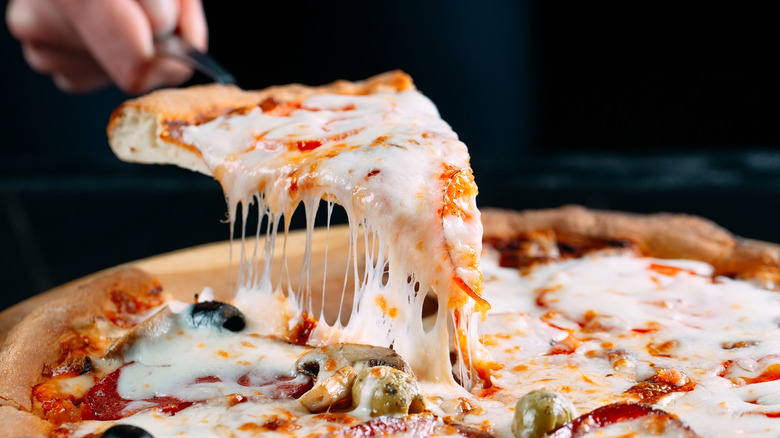 Hand serving a slice of pizza