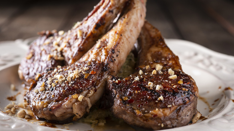 Seared lamb chops with seasoning on wood board