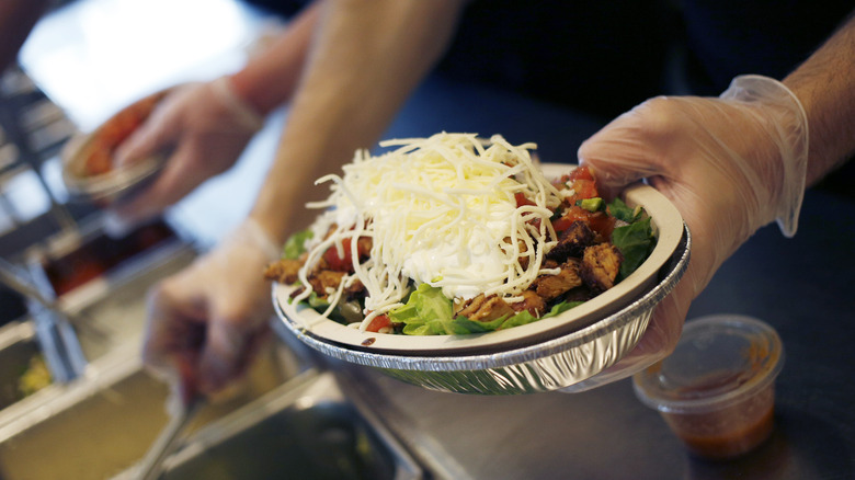 worker making Chipotle burrito bowl