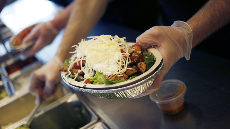 Chipotle employee holding a burrito bowl