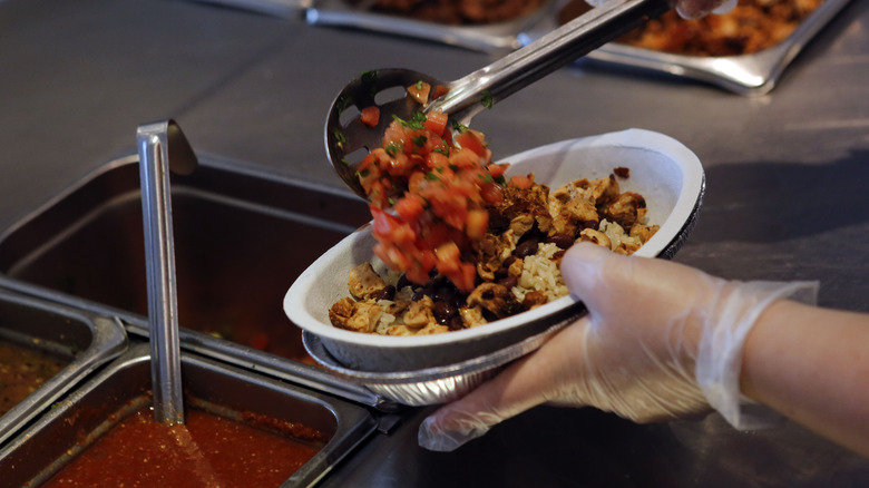 A Chipotle employee makes a bowl