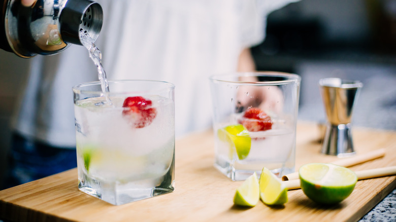 A stream of clear liquid pours from a shaker into a glass