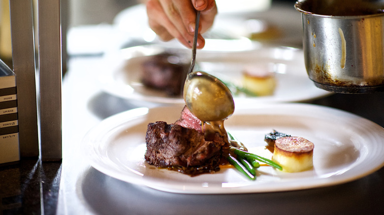 sauce being poured over steak