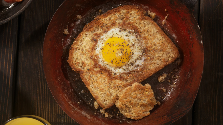 Egg in a hole in a pan placed on a wooden table