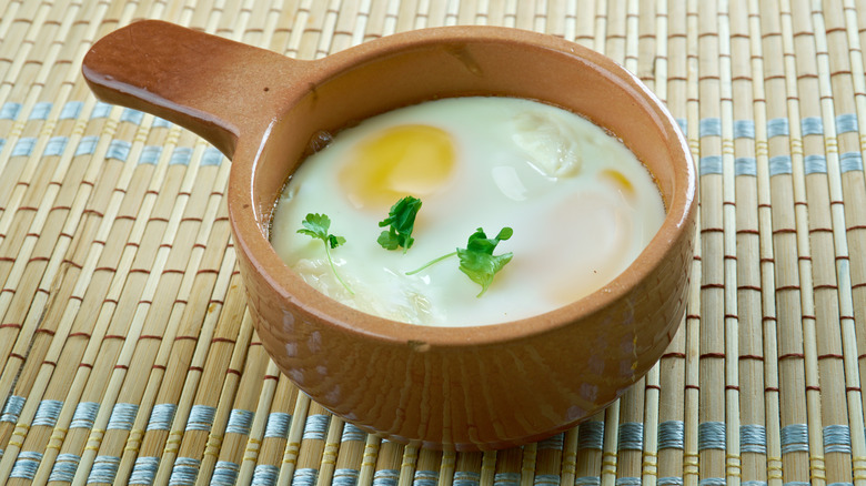 Shirred eggs in a rustic bowl placed on a table