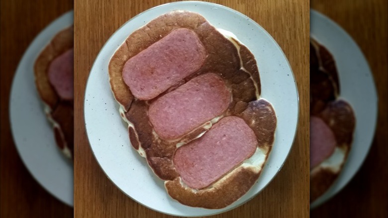 Spam cakes on a white plate placed on a wooden table