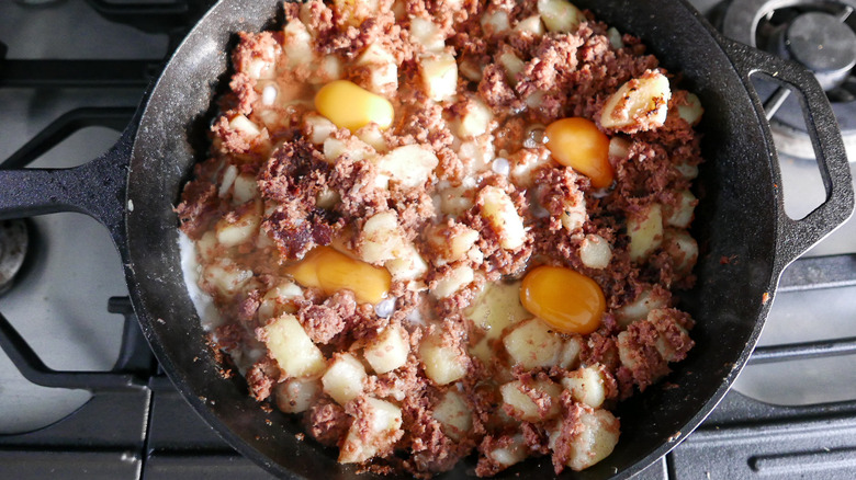 cracked eggs in skillet with hash
