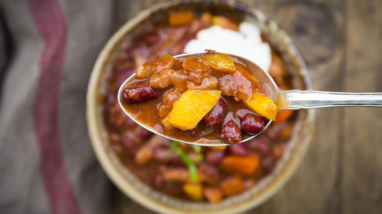 Close-up on a spoonful of chili over a bowlful