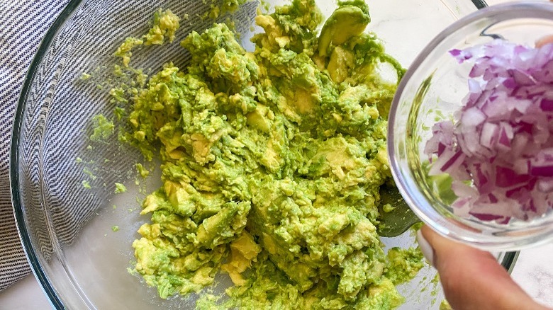 mashed avocado in bowl with red onion