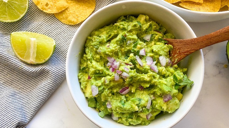 guacamole in a bowl with chips and lime