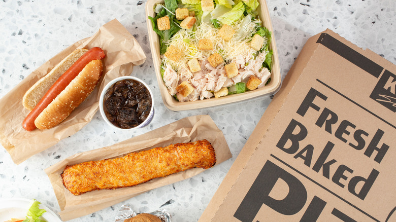 An overhead view of Costco food court items, including its hot dog, chicken bake, and chicken caesar salad