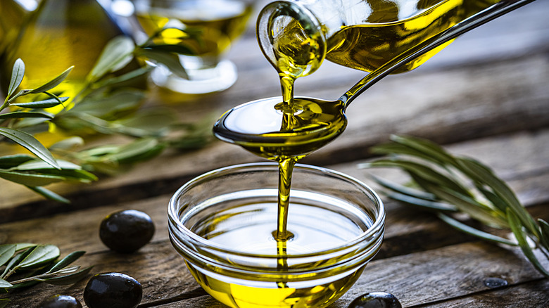 Olive oil being poured from bottle into bowl
