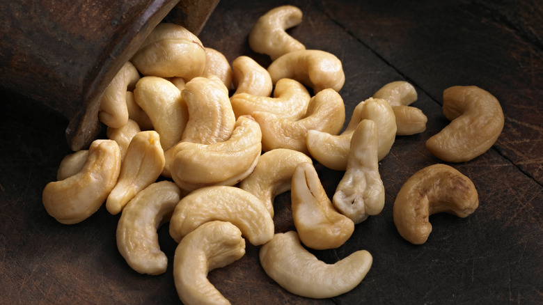 Whole cashews spilling from bowl onto table