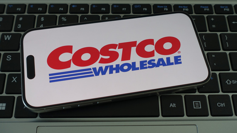 Phone open to Costco Wholesale app on laptop keyboard