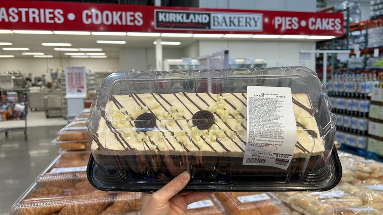 Person holding up a Costco Mocha Crunch Bar Cake in the bakery