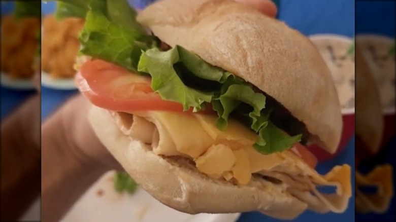 Closeup of a chicken and bacon sandwich with cheese, tomato, and lettuce