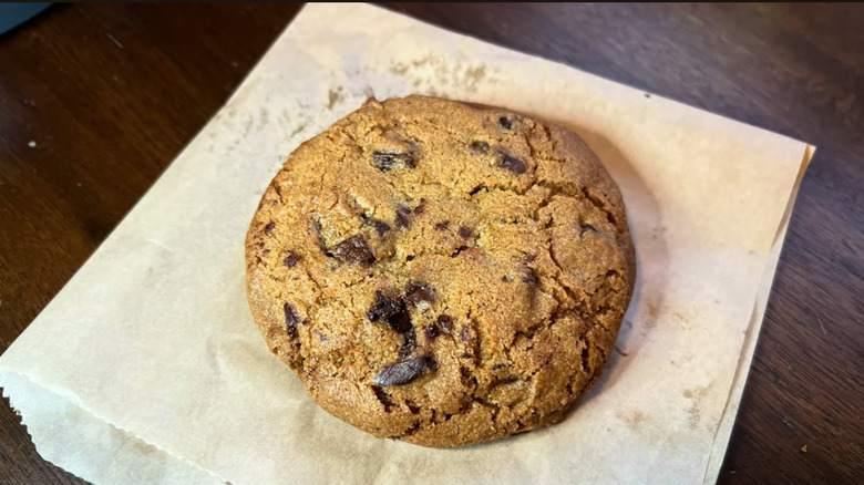 A Costco food court Double Chocolate Chunk Cookie sitting on top of its wax paper on a table