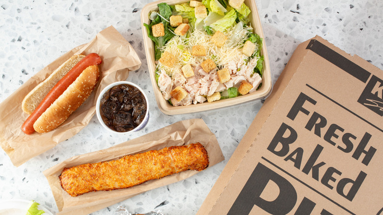 an assortment of Costco food court items, including hot dog, chicken bake, pizza, salad, and drink