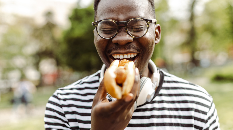 Man smiling holding hot dog