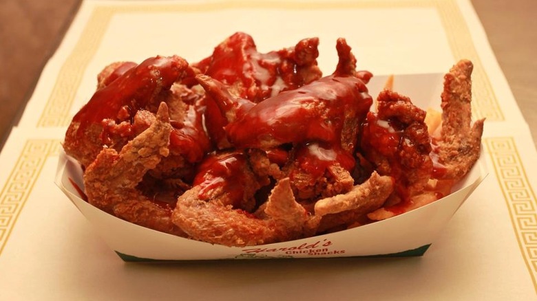 a basket of Harold's fried chicken wings with gleaming red mild sauce poured over