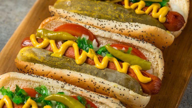 a row of Chicago-style hot dogs on a wooden board