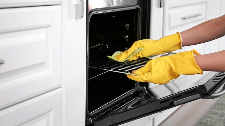 Person cleaning oven with rag