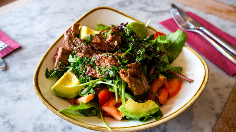 Steak salad with avocado in bowl