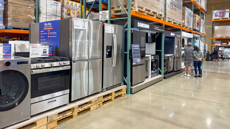 Aisle of kitchen appliances at a Costco where a couple peruses in the distance