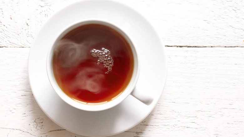 White teacup and saucer full of hot black tea