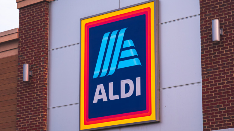 An Aldi sign mounted on a white wall with brick trim