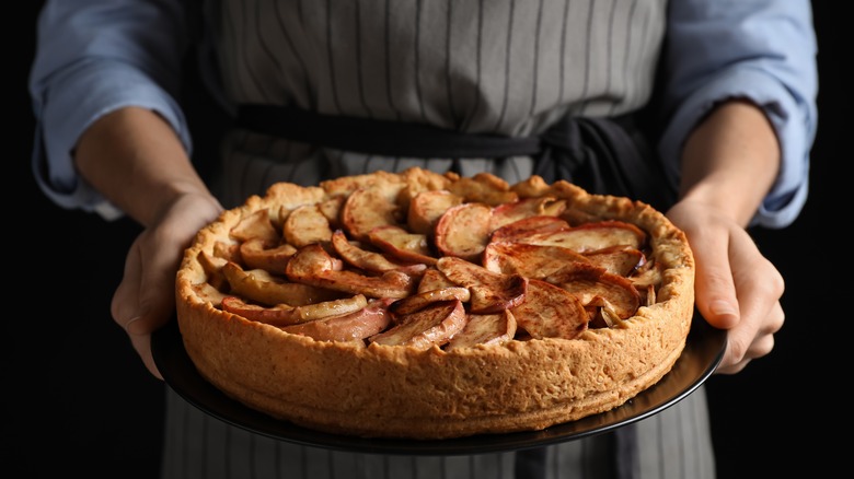 Woman holding apple pie on plate