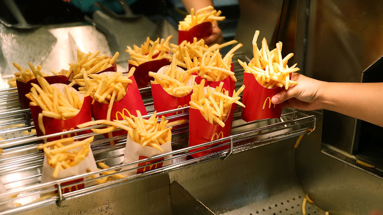 Hand adds McDonald's fries container to heated, ready-to-go section