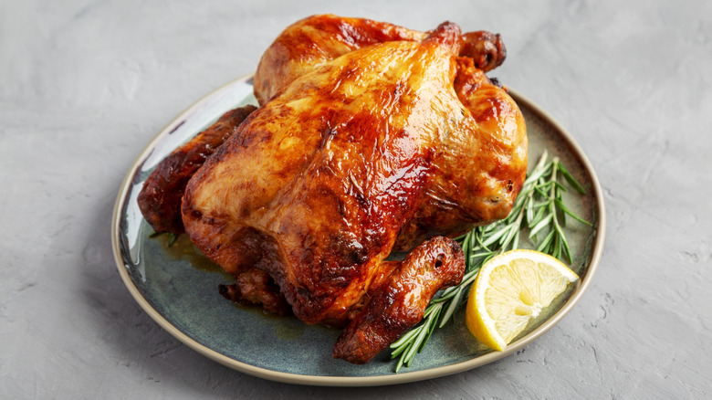 Rotisserie chicken on plate with garnish and lemon wedge