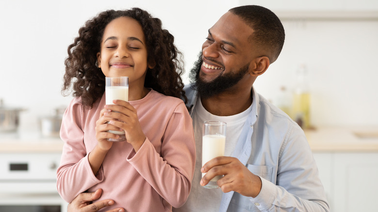 African-American dad giving milk to daughter