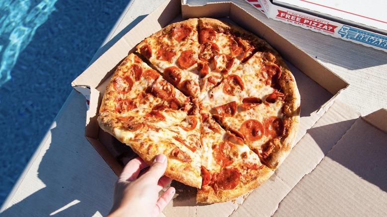 Hand grabbing slice of Domino's pepperoni pizza