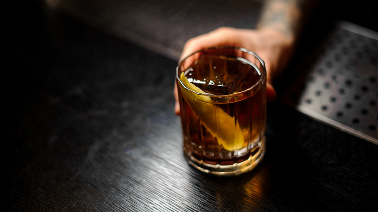 A bartender serves a whisky cocktail